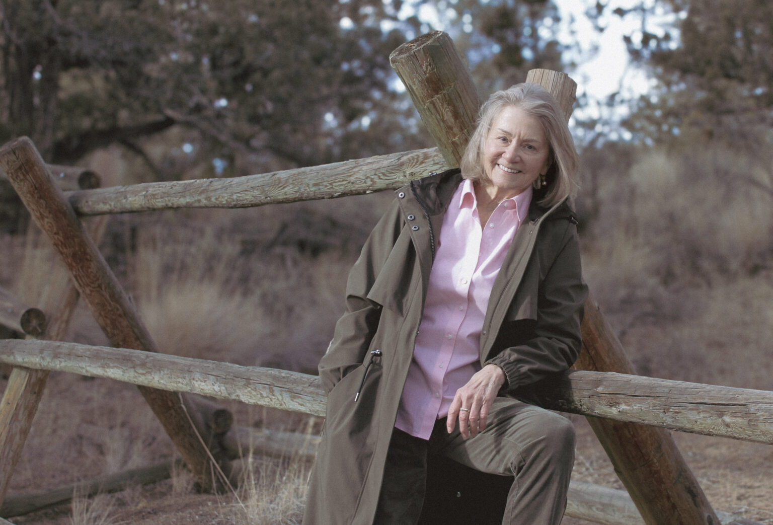 Oregon Poet Laureate Ellen Waterston leans against a wood fence in the desert sun.